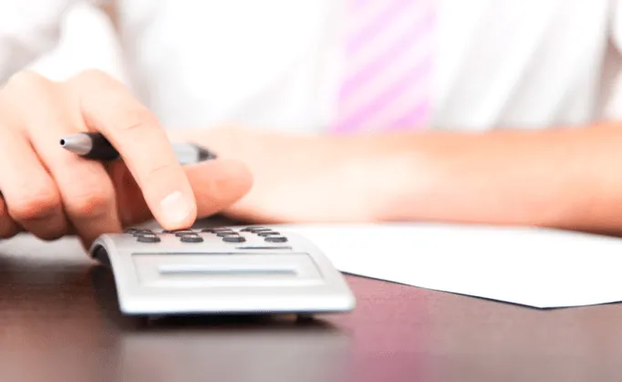 Personne calculant le coût des obsèques sur une calculatrice de bureau.