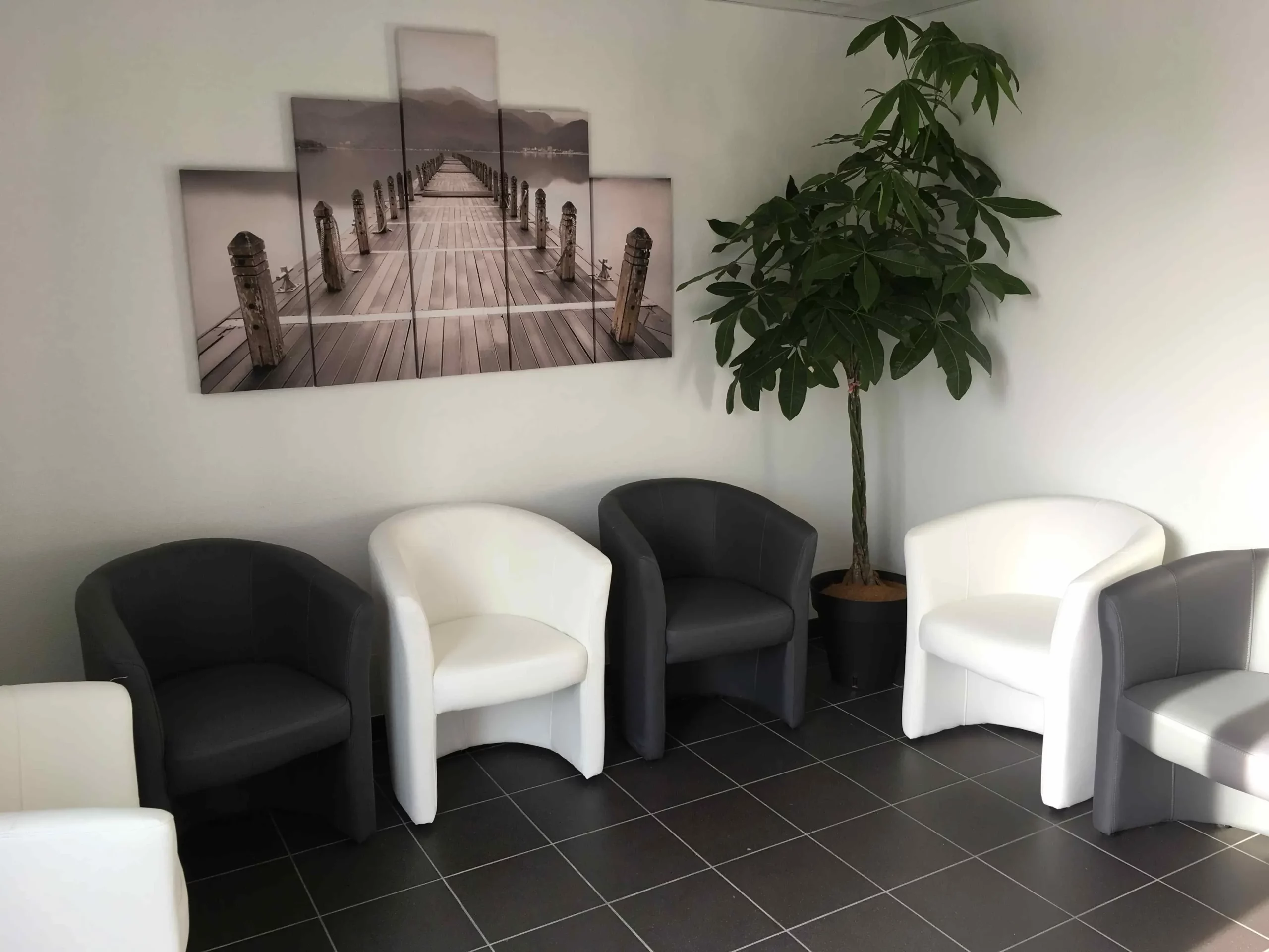 Espace d'attente du funérarium avec fauteuils et plante verte.
